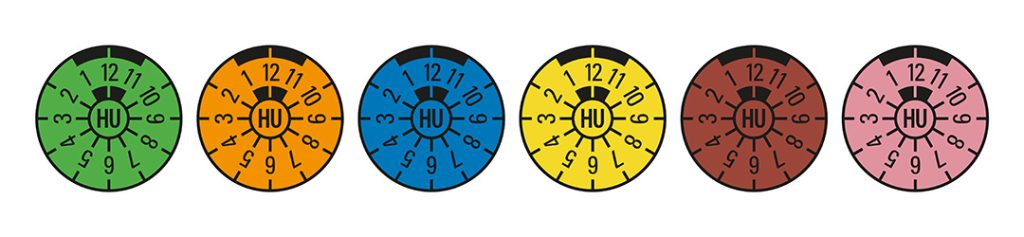 Die Grafik zeigt die sehcs aufeinanderfolgenden Farben der HU-Plaketten: Grün, Orange, Blau, Gelb, Braun, Rosa, die jährlich im Wechsel vergeben werden.