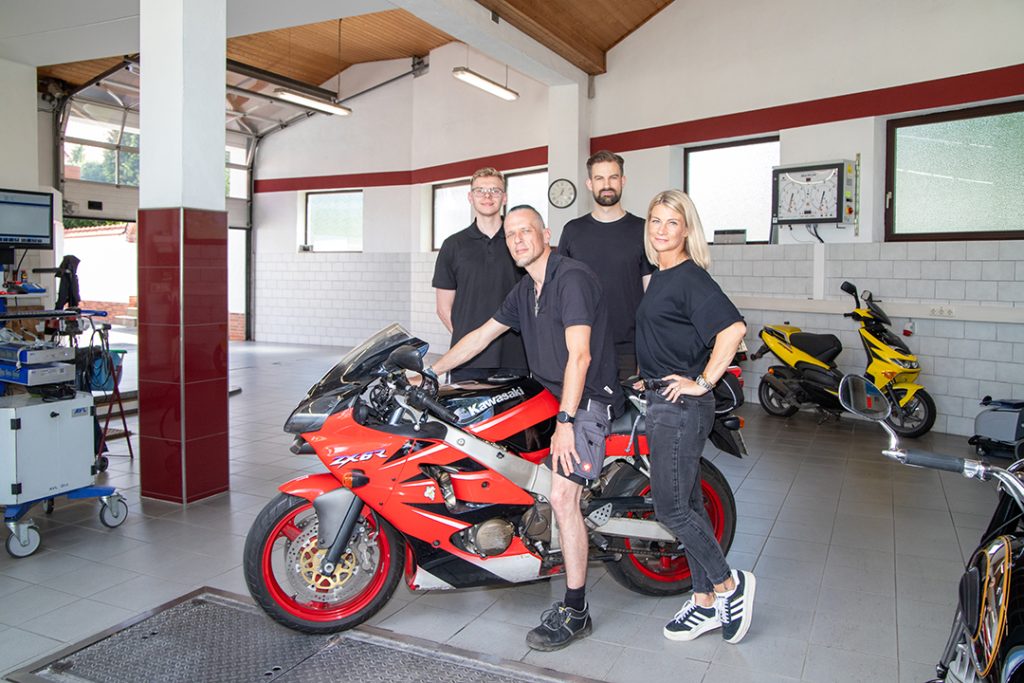 Das Bild zeigt vier Prüfingenieure des Prüfcenter Ebert, die um ein Motorrad versammelt sind.